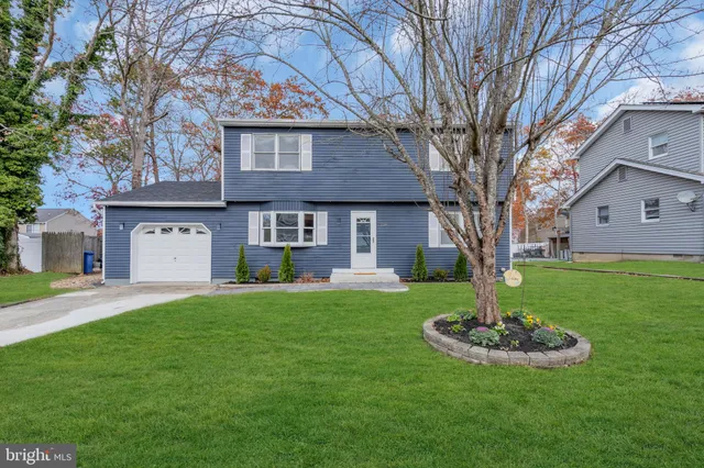 a front view of a house with a yard and tree
