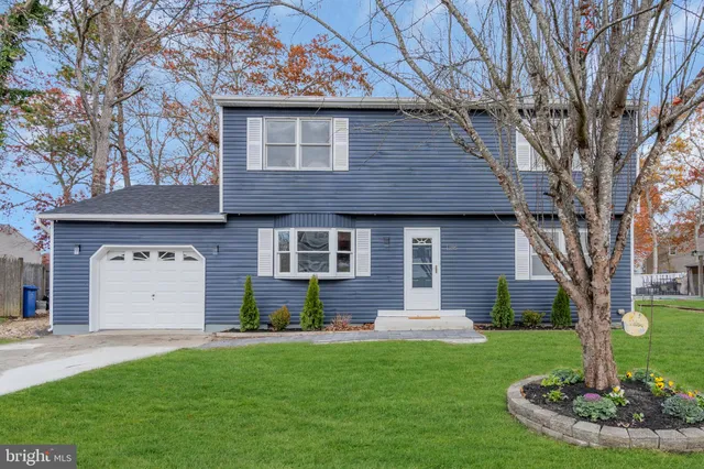 a front view of a house with a garden and trees