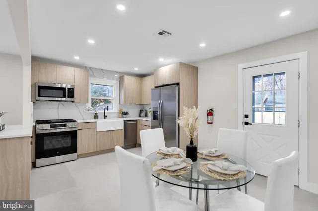 a kitchen with stainless steel appliances kitchen island granite countertop a stove a sink a refrigerator a dining table and chairs