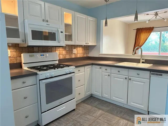 a kitchen with cabinets appliances a sink and a window