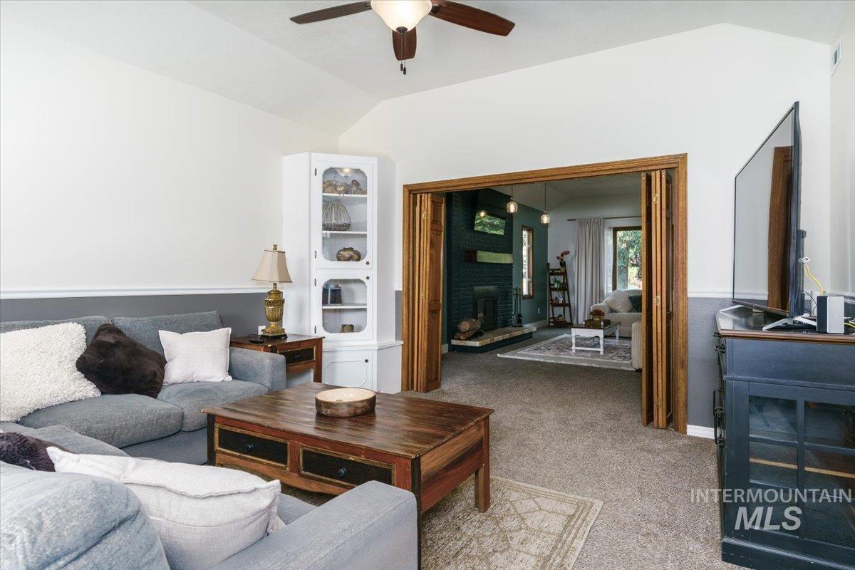 1401 Chokecherry Drive Pocatello, ID 83204 - Photo 9 of 46 Vaulted ceilings define this living area, featuring a two-tone wall treatment, carpet flooring, and a ceiling fan