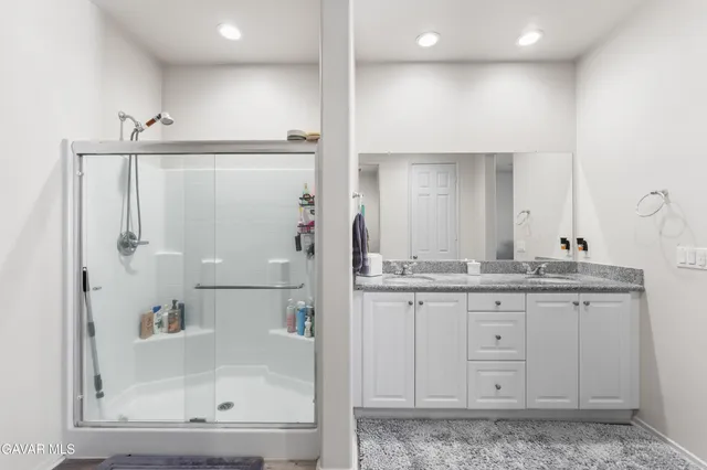 a bathroom with a granite countertop sink mirror and shower