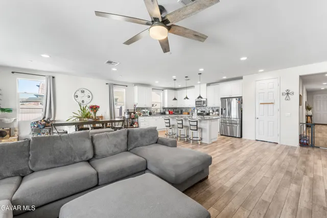 a living room with furniture with kitchen view and a chandelier