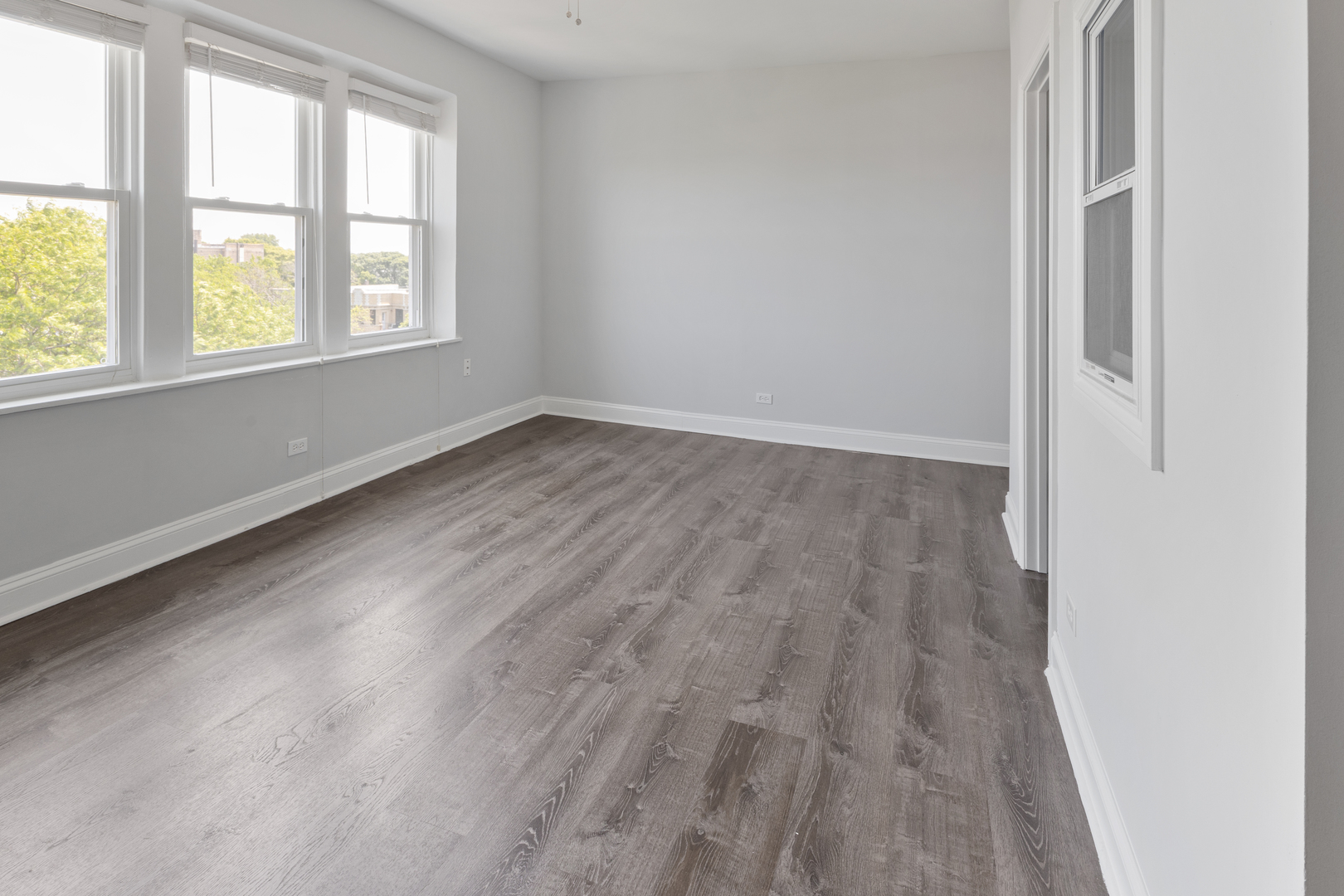 1608 West Sherwin Avenue, Unit 608 Chicago, IL 60626 - Photo 3 of 13 an empty room with wooden floor and windows