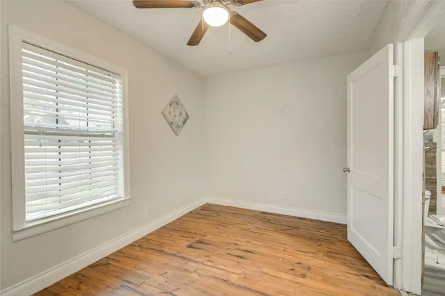 a view of empty room with wooden floor and fan