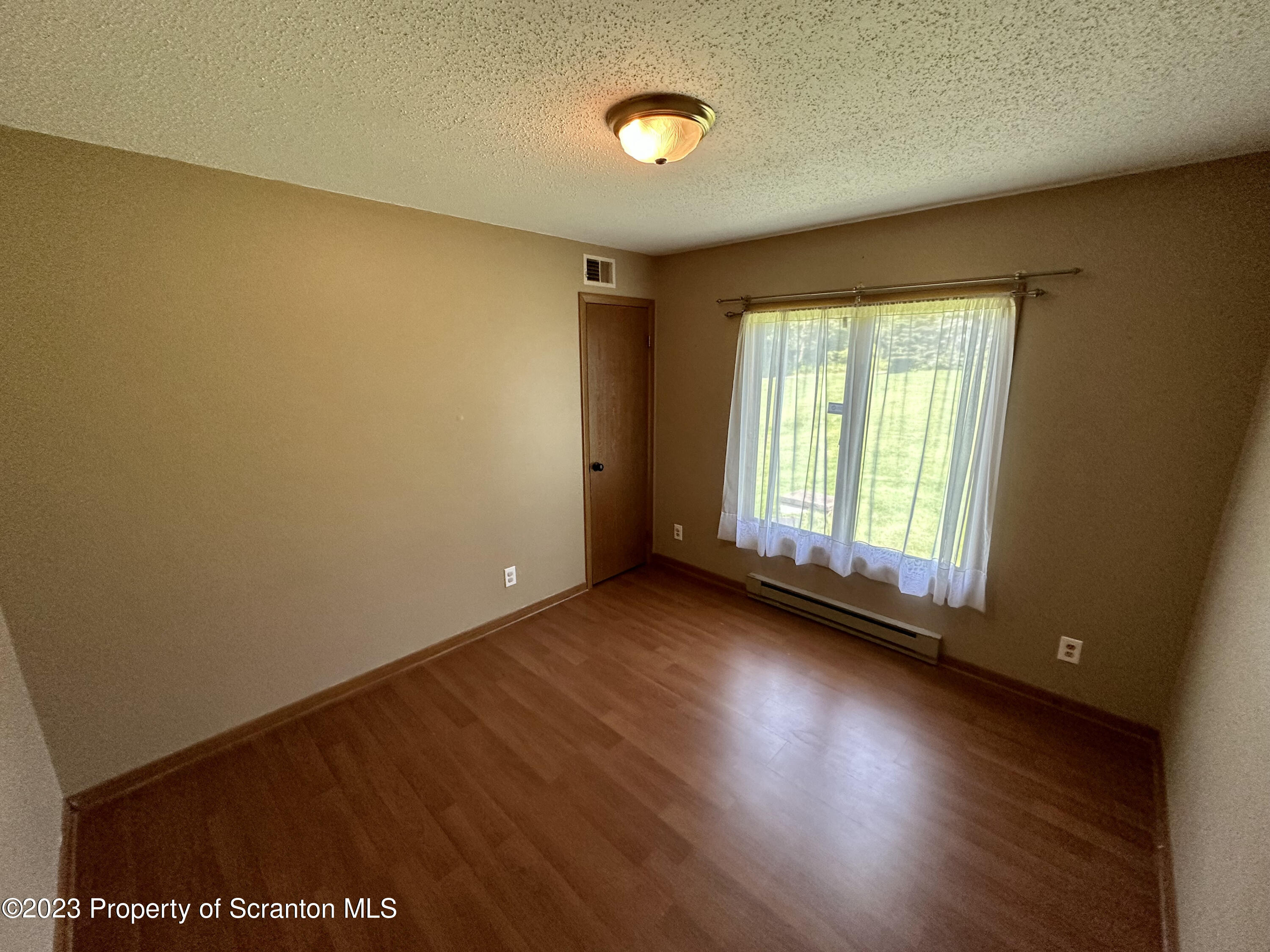 764 Coon Road Wyoming, PA 18644 - Photo 11 of 23 an empty room with wooden floor and windows