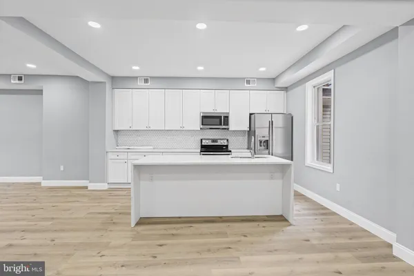 a kitchen with stainless steel appliances kitchen island granite countertop a refrigerator and a stove top oven