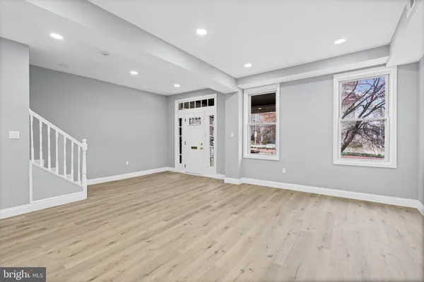 a view of an empty room with window and wooden floor