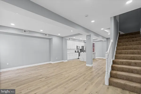 a view of an empty room with wooden floor and stairs