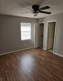a view of an empty room with wooden floor and a window
