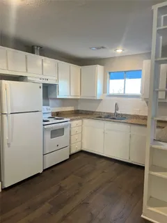 a kitchen with granite countertop white cabinets and white appliances
