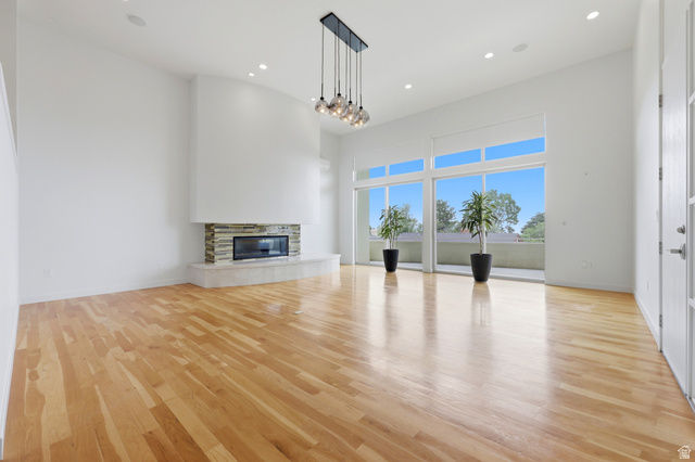 1389 Millbrook Way Bountiful, UT 84010 - Photo 16 of 74 Spacious living area featuring light wood-finish flooring, a stone-clad fireplace, and expansive floor-to-ceiling windows