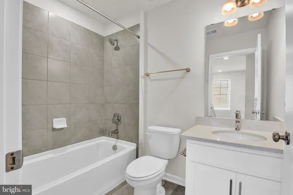 a bathroom with a sink a toilet a mirror a bathtub and shower