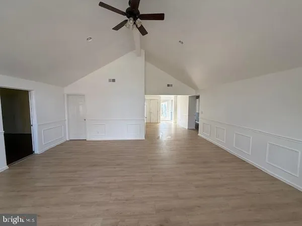 an empty room with wooden floor fan and windows
