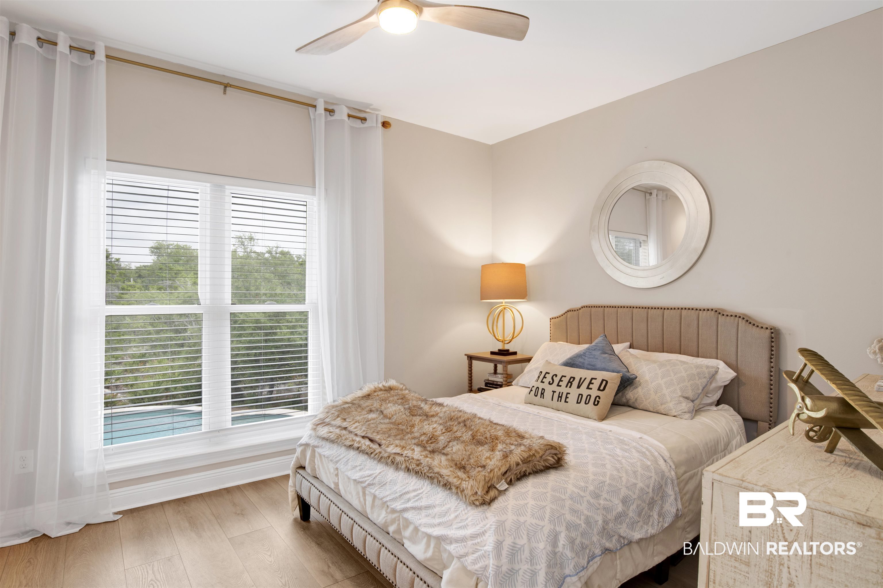 30351 River Road Orange Beach, AL 36561 - Photo 22 of 44 Natural light fills this room featuring wood-finish flooring, a contemporary ceiling fan, and a large window overlooking a pool