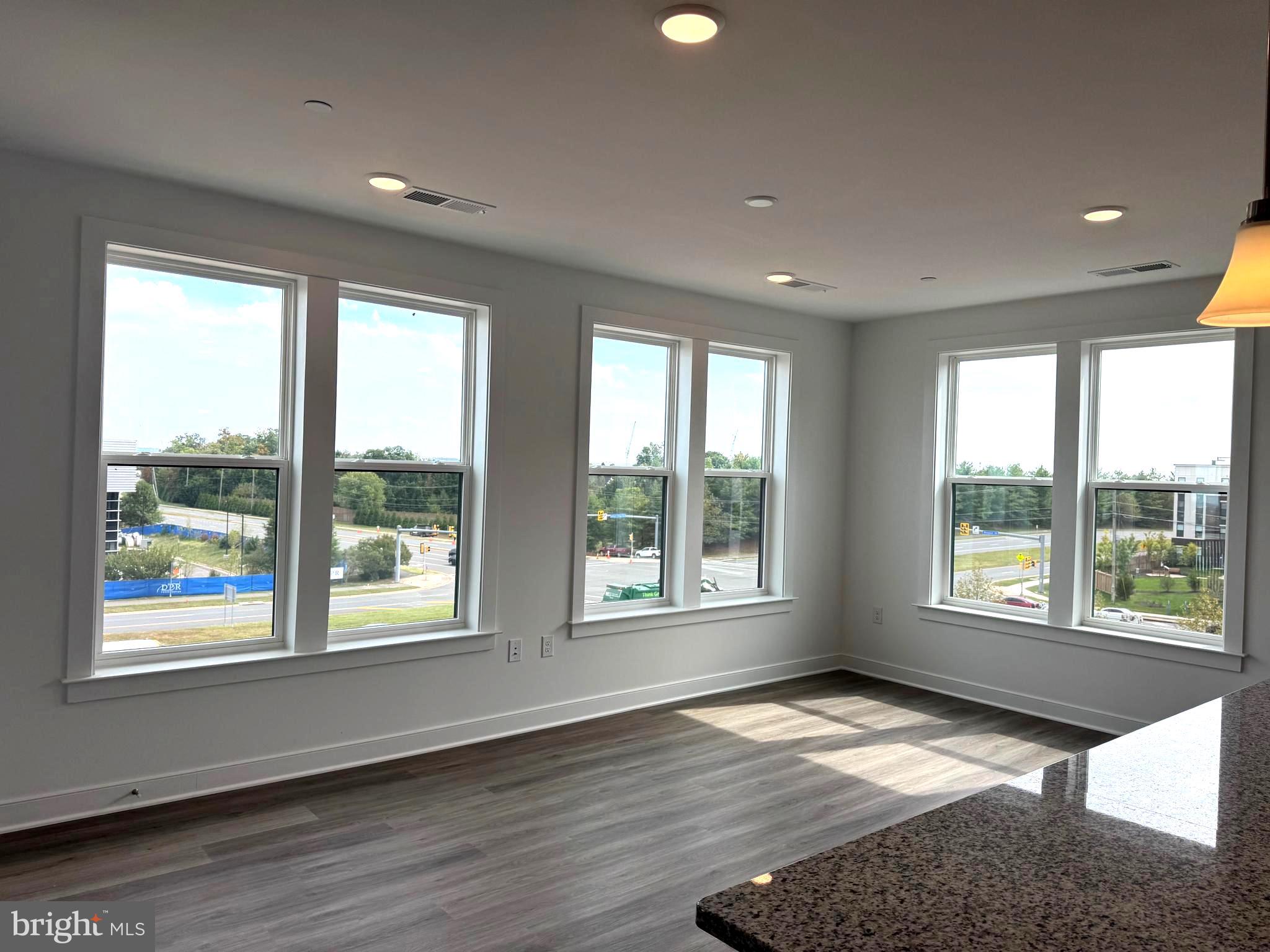 21731 Dovekie Terrace, Unit 408 Ashburn, VA 20147 - Photo 2 of 20 a view of an empty room with wooden floor and a window