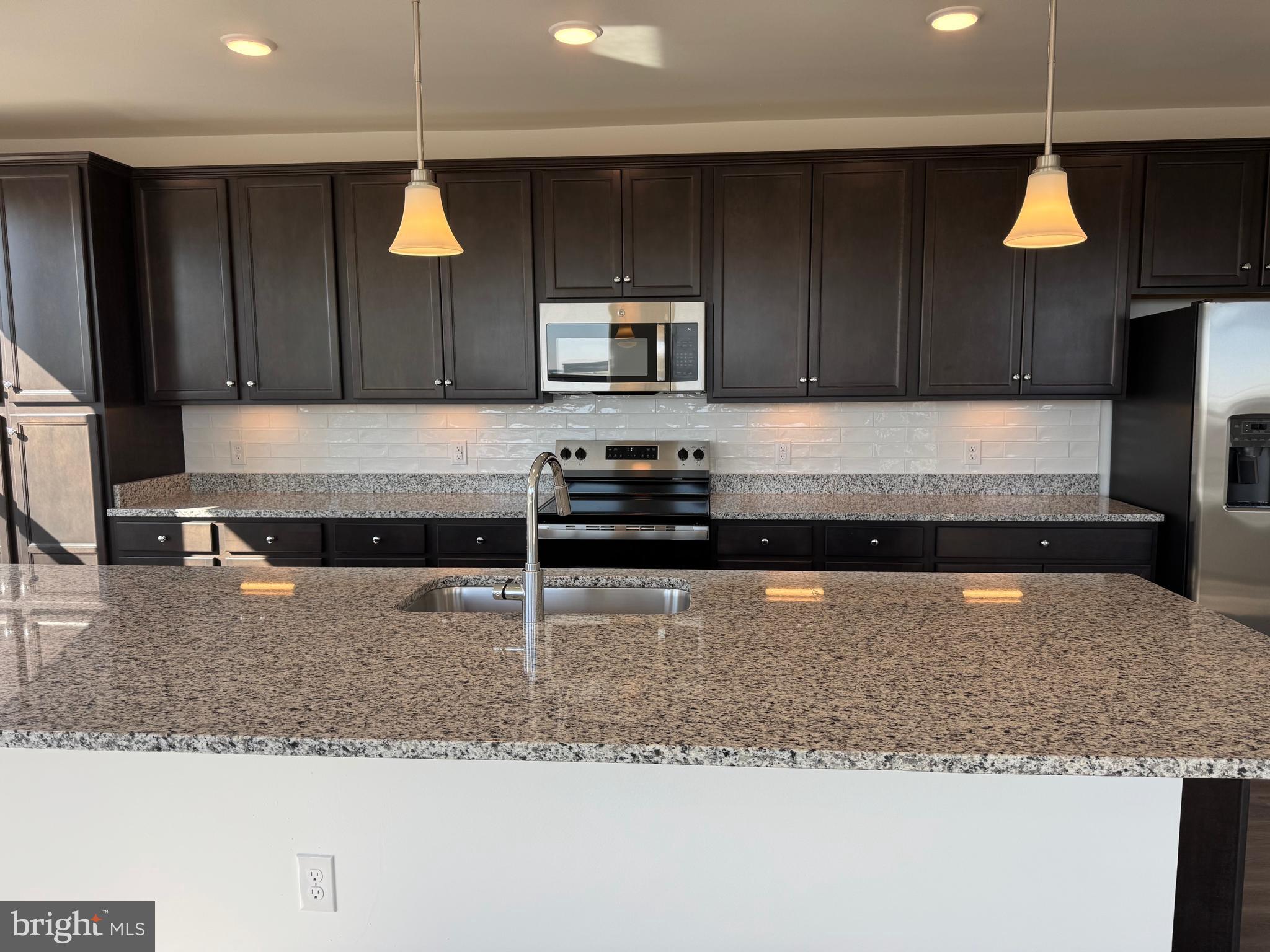 21731 Dovekie Terrace, Unit 408 Ashburn, VA 20147 - Photo 8 of 20 a kitchen with stainless steel appliances granite countertop a stove a sink and a microwave