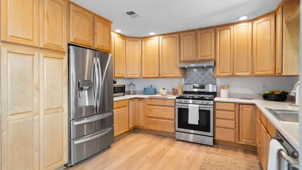 a kitchen with stainless steel appliances granite countertop white cabinets a stove top oven a sink and dishwasher
