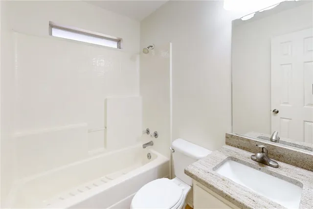 a bathroom with a granite countertop bathtub shower sink vanity mirror and toilet