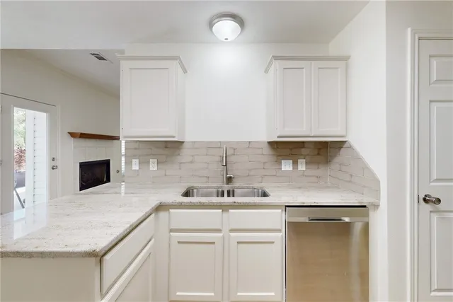 a kitchen with a sink dishwasher a stove and a microwave oven with white cabinets