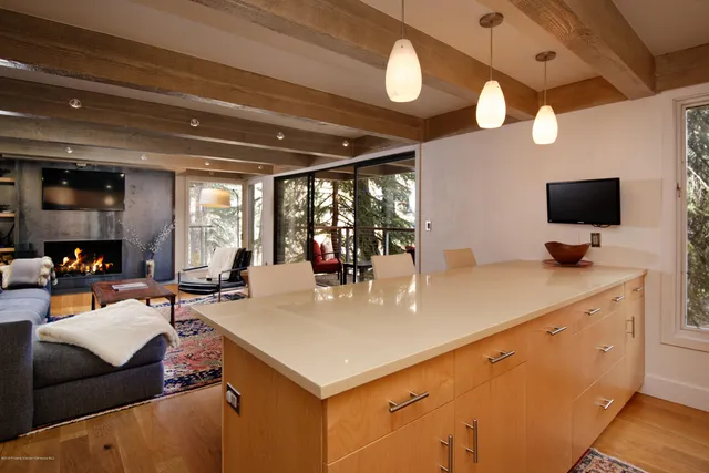 a kitchen with stainless steel appliances granite countertop a sink a stove a refrigerator cabinets and a dining table with wooden floor