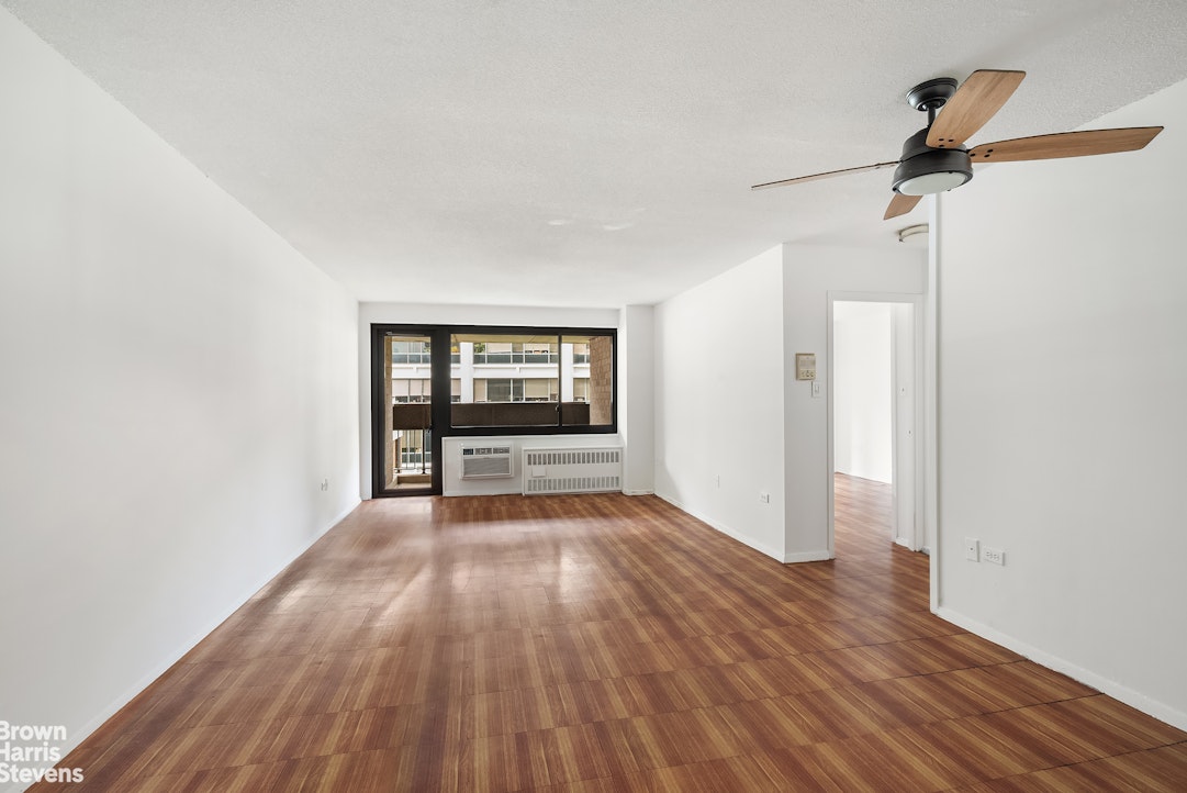 a view of an empty room with a window and wooden floor