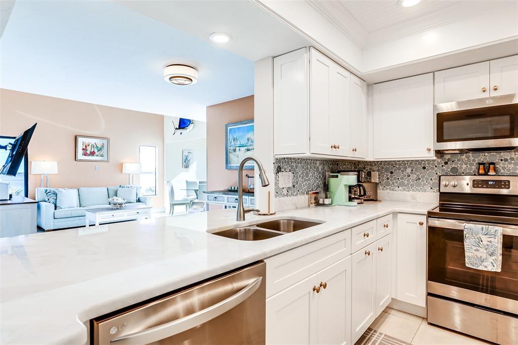 2955 North Beach Road, Unit A432 Englewood, FL 34223 - Photo 9 of 24 a kitchen with kitchen island granite countertop a sink and white cabinets