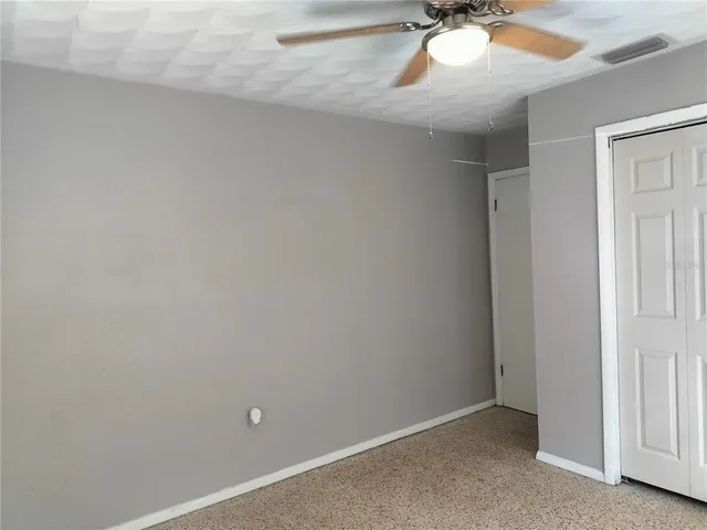 a view of a room with a ceiling fan and carpet