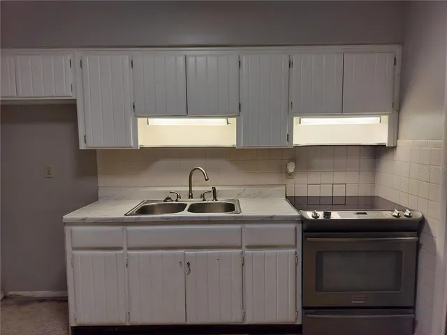 a kitchen with white cabinets a sink and dishwasher