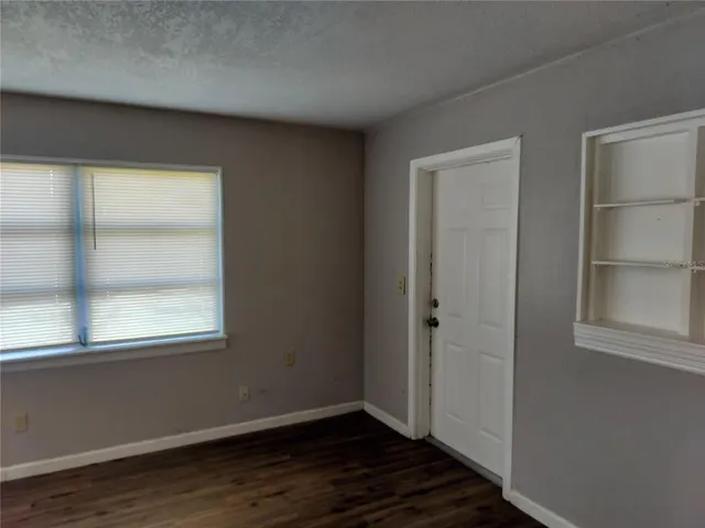 an empty room with wooden floor closet and windows