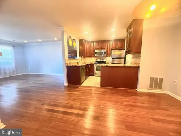 a view of a kitchen with kitchen island a sink wooden floor and a counter top space