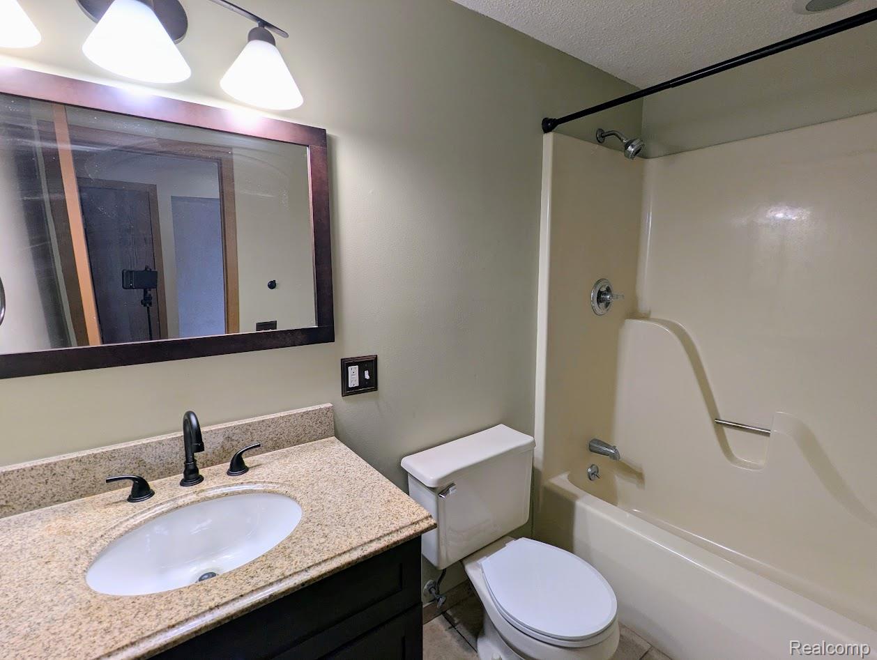 2316 Crescent Lake Road Waterford, MI 48329 - Photo 7 of 17 Bathroom featuring a cream-colored bathtub/shower combination, dark bronze shower rod, and a vanity with a granite countertop and dark bronze faucet