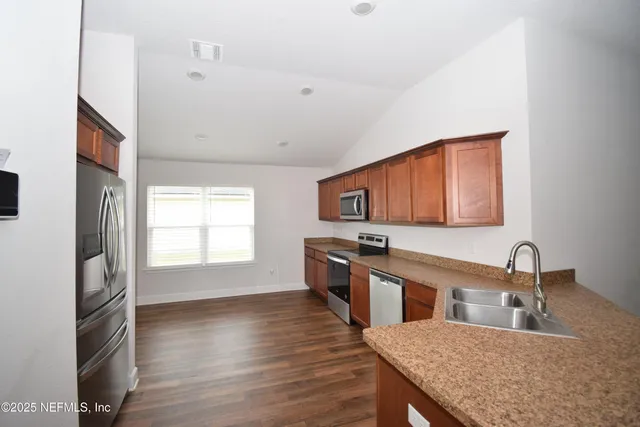 a kitchen with stainless steel appliances granite countertop a sink dishwasher stove and wooden floor