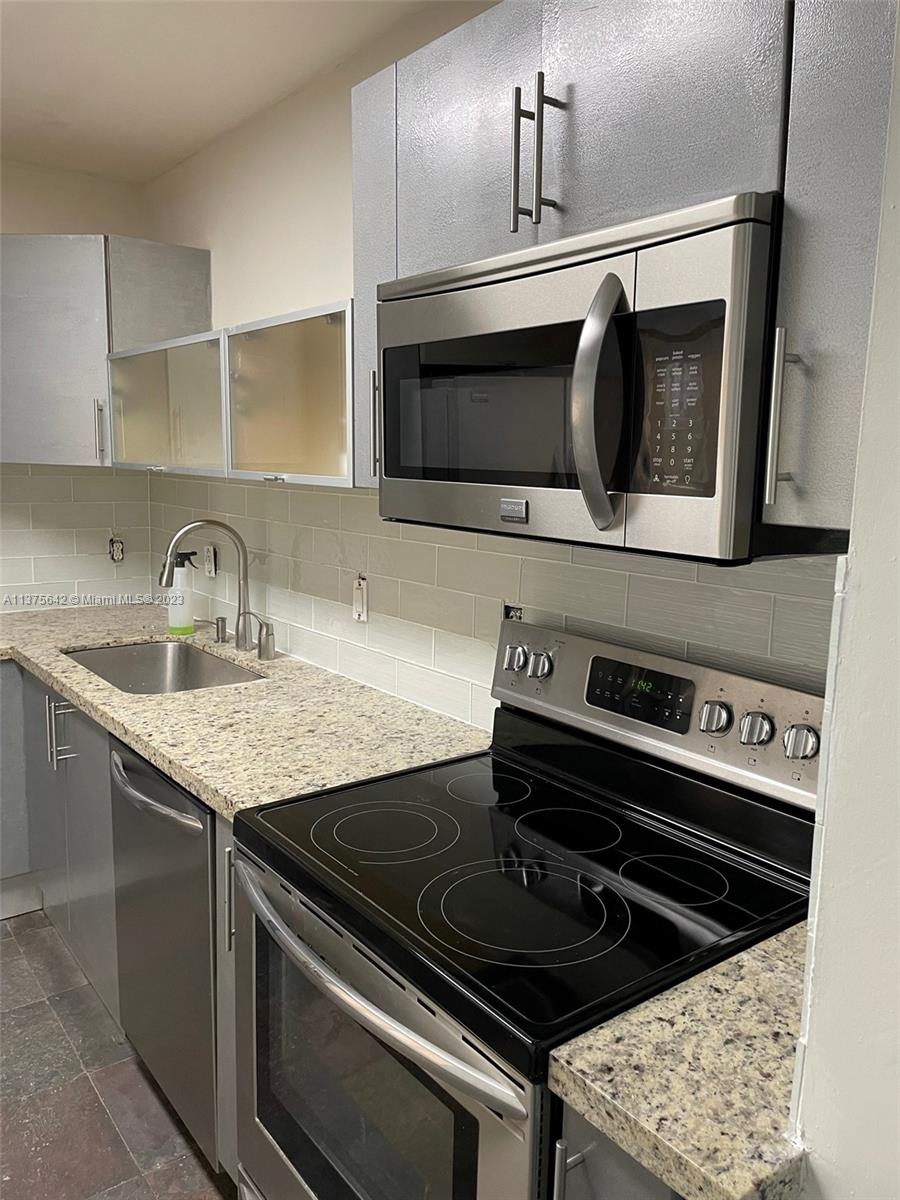 Normandy Beach Surfside, FL 33154 - Photo 16 of 32 a kitchen with granite countertop a stove microwave and sink
