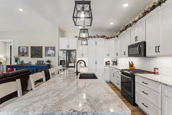 a kitchen with stainless steel appliances kitchen island granite countertop a sink dishwasher a stove a refrigerator and cabinets with wooden floor