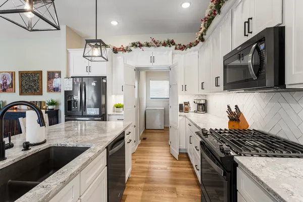 a kitchen with stainless steel appliances granite countertop a sink a stove and a refrigerator