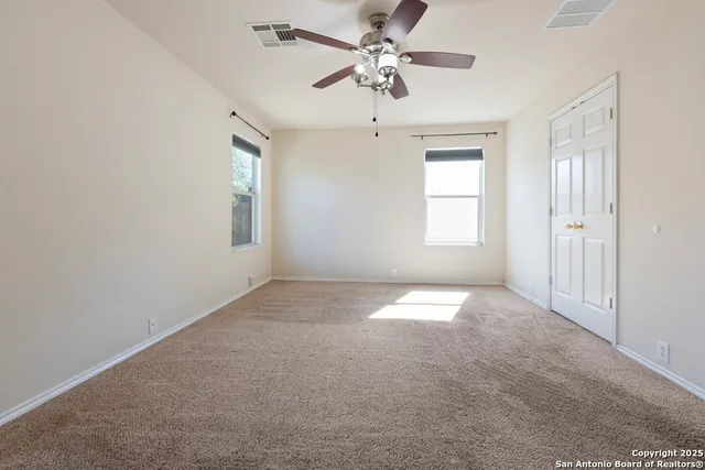 en empty room with windows and ceiling fan