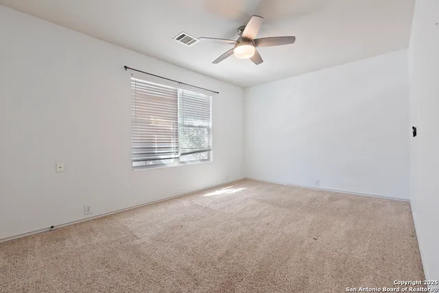 an empty room with windows and ceiling fan