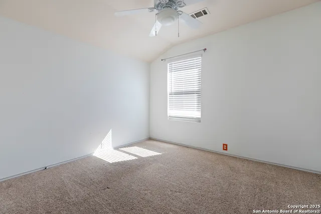 an empty room with a chandelier fan and windows