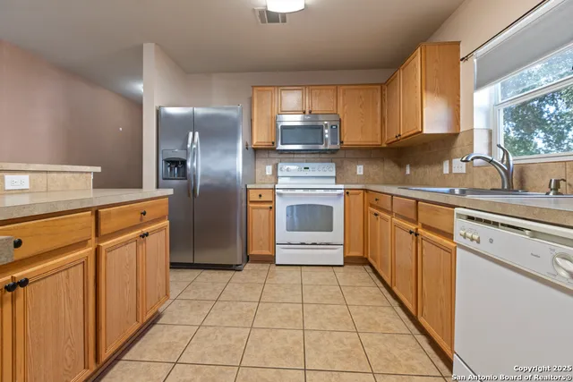 a kitchen with stainless steel appliances granite countertop a refrigerator and a stove top oven