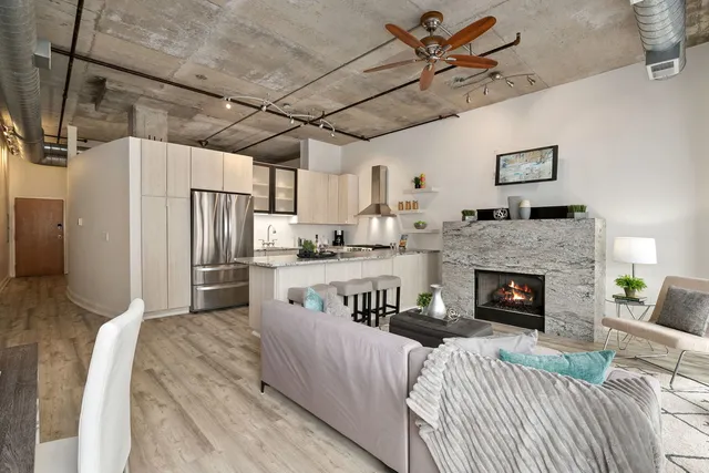 a living room with stainless steel appliances furniture a fireplace and a chandelier
