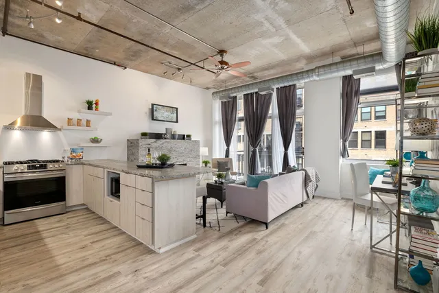 a kitchen with granite countertop a stove top oven a sink dishwasher and white cabinets with wooden floor