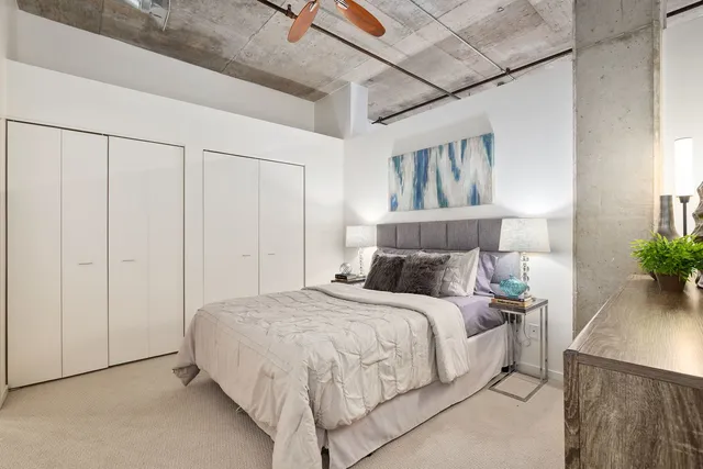 a bedroom with a large bed and a potted plant on the dresser