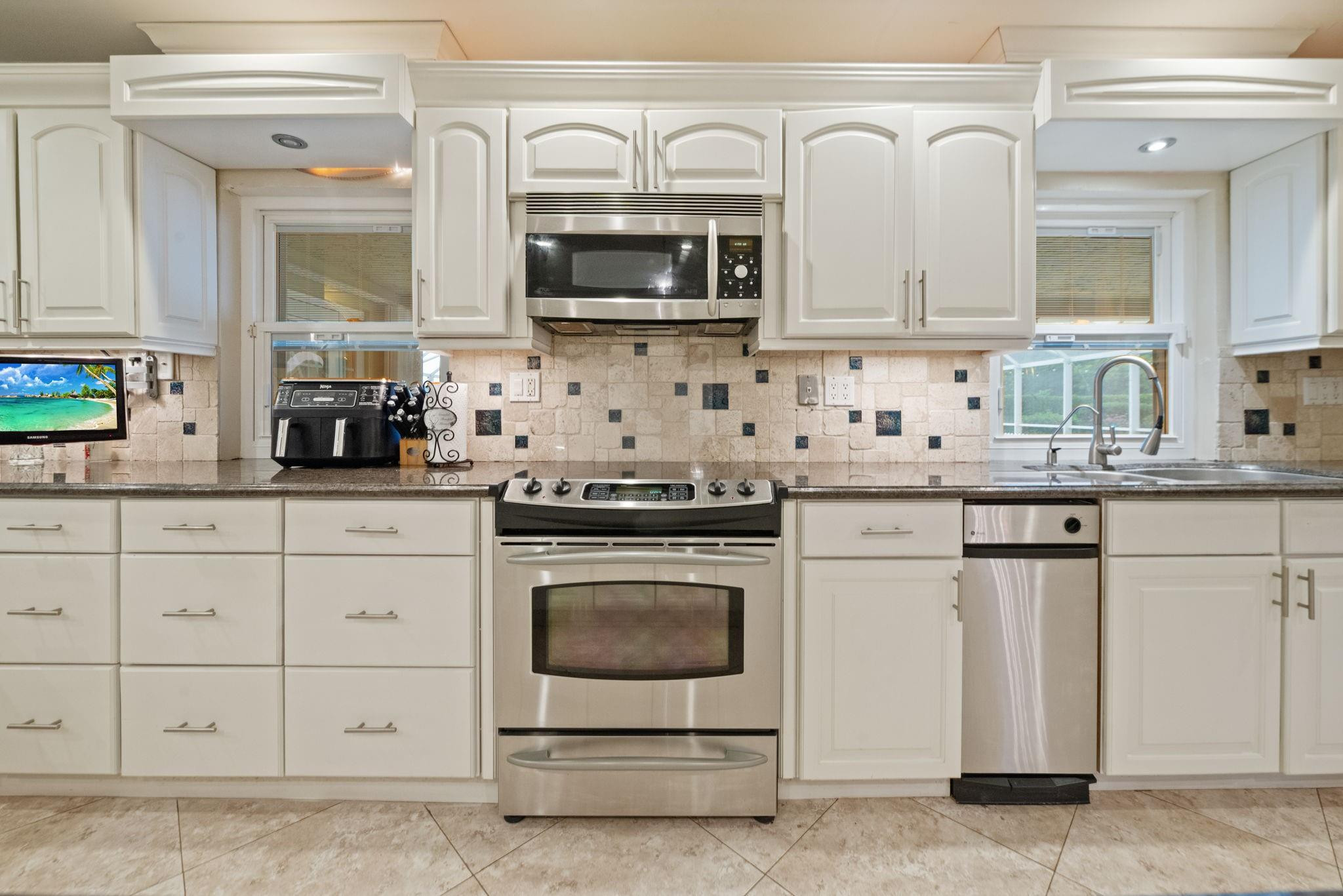 17501 Southwest 54th Street Southwest Ranches, FL 33331 - Photo 19 of 39 a kitchen with stainless steel appliances granite countertop a sink a stove a microwave and cabinets