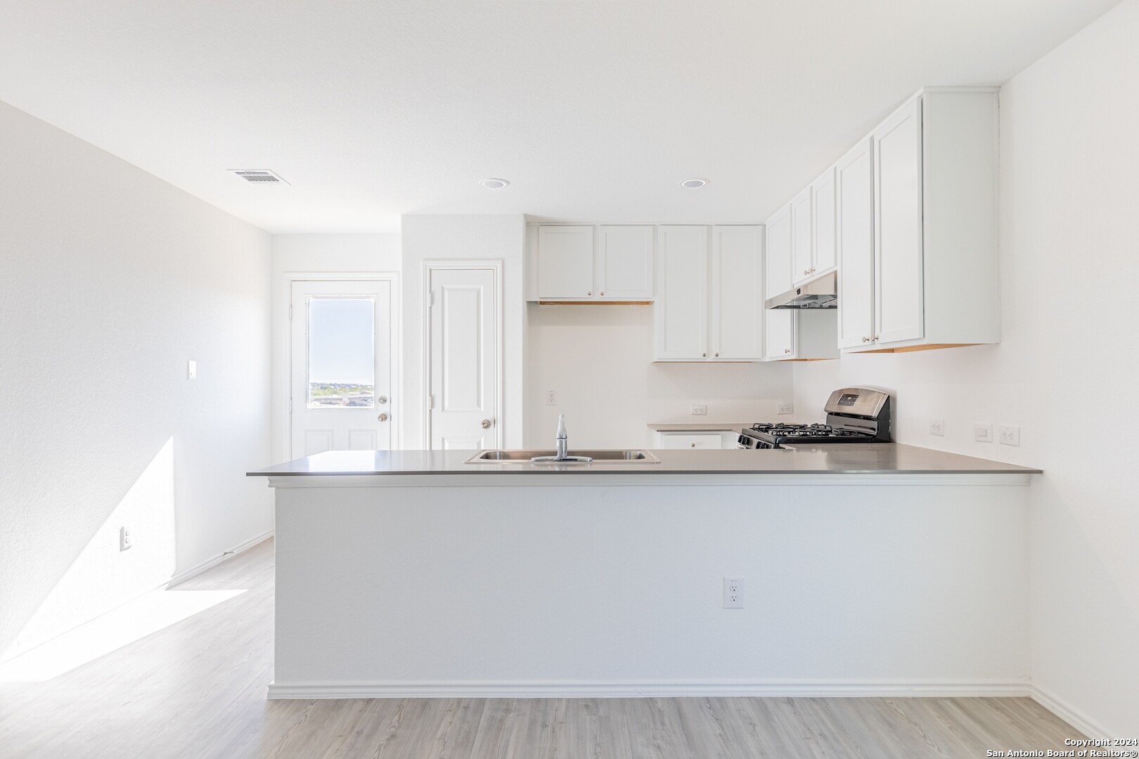 1631 Knoll Ridge New Braunfels, TX 78130 - Photo 13 of 29 a kitchen with stainless steel appliances granite countertop a sink a stove and white cabinets