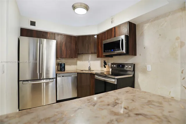 a kitchen with granite countertop a refrigerator stove and microwave