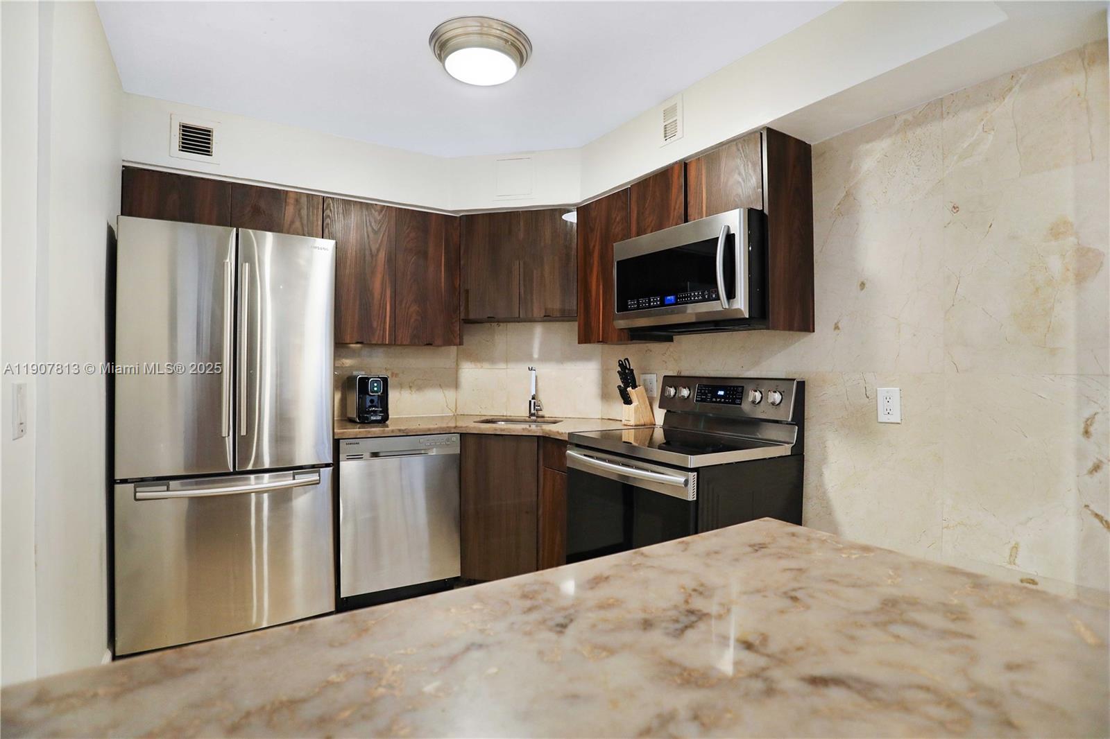 5225 Collins Avenue, Unit 1216 Miami Beach, FL 33140 - Photo 12 of 49 a kitchen with granite countertop a refrigerator stove and microwave