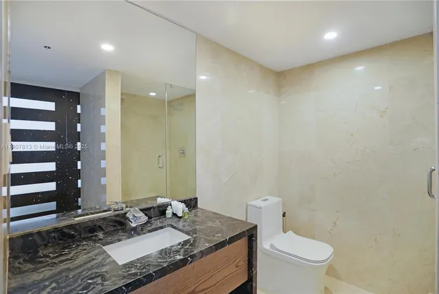 a bathroom with a granite countertop sink a toilet and shower