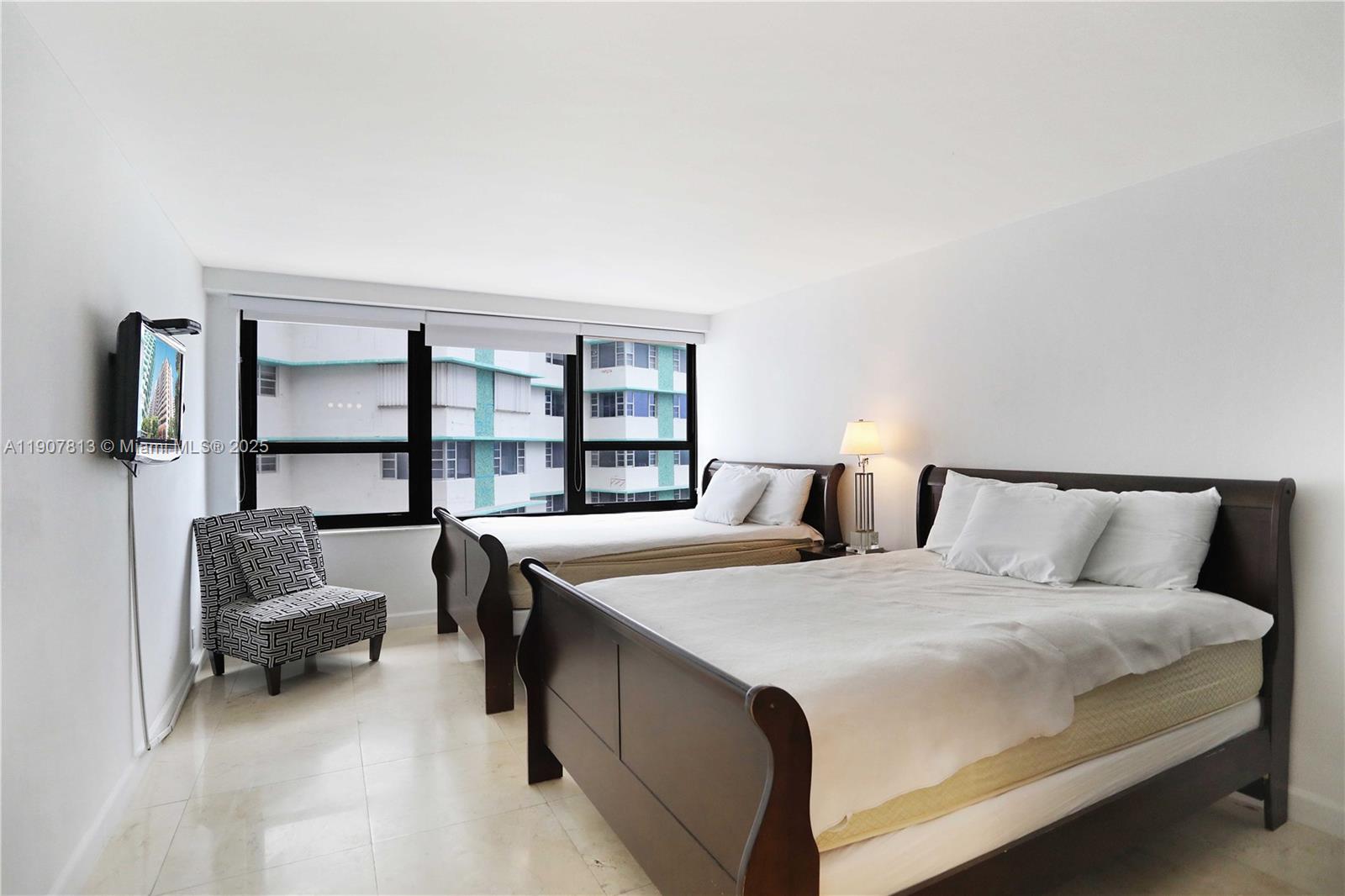 5225 Collins Avenue, Unit 1216 Miami Beach, FL 33140 - Photo 29 of 49 a large bedroom with a bed and a chair