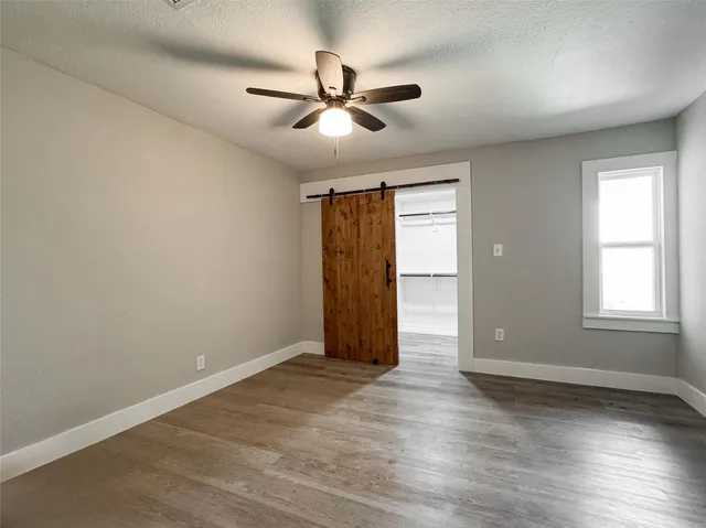 an empty room with wooden floor ceiling fan and windows